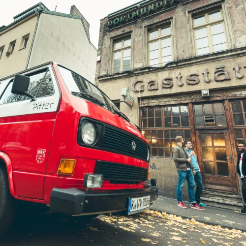 Roter Tourbulli vor einer historischen Kölner Gaststätte