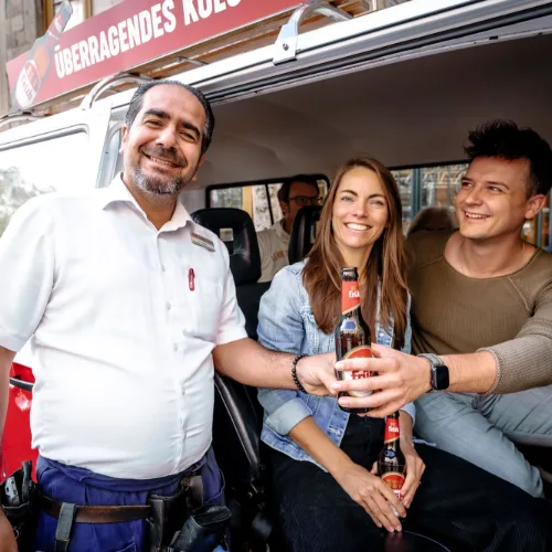 Guide und Gäste stoßen im Bulli mit Kölsch an