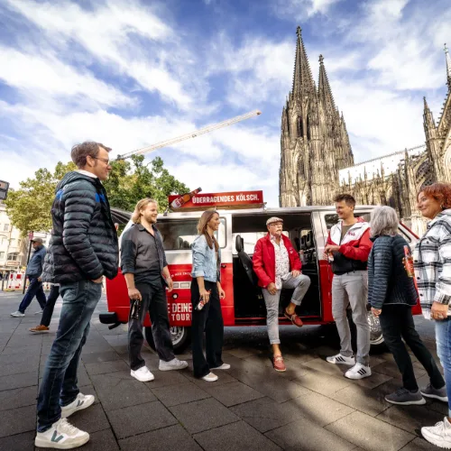 Tourgruppe steht mit dem Bulli vor dem Kölner Dom