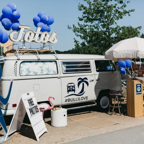 Weißer Fotobulli mit blauen Ballons und Fotos-Schriftzug