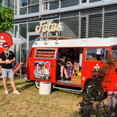 Roter Fotobulli mit Gästen bei einem Sommerfest