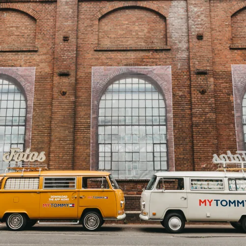 Gelber und weißer Fotobulli vor einer historischen Industriehalle
