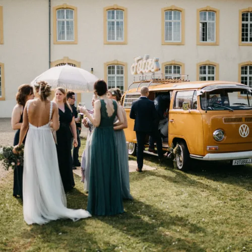 Hochzeitsgesellschaft am Fotobulli vor einem Herrenhaus